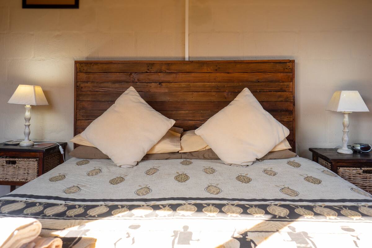 A bed with a wooden headboard, two pillows, a patterned bedspread, and two bedside tables with lamps and a basket.