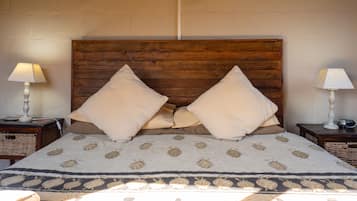 Una cama con cabecera de madera, dos almohadas, un edredón estampado y dos mesitas de noche con lámparas y una cesta.