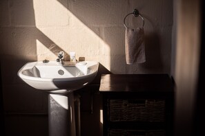 A bathroom with a white sink, a wooden cabinet, and a towel hanging on a metal ring.