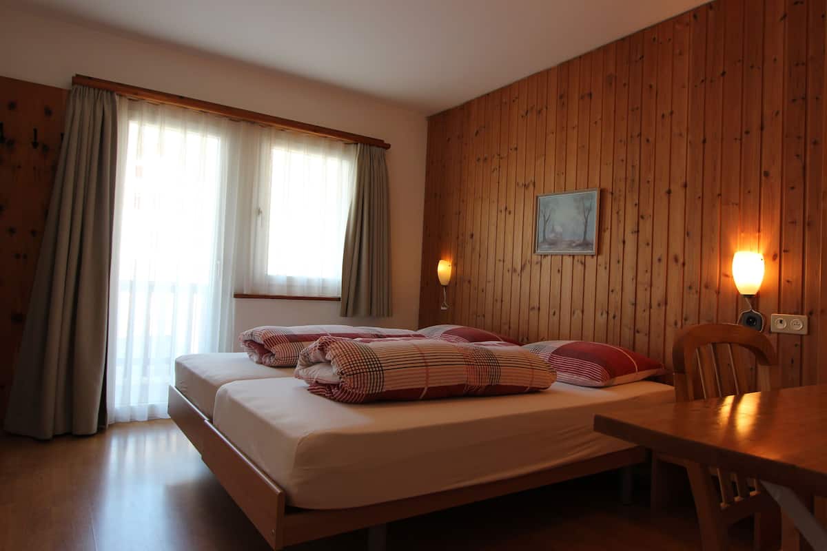 A room with a bed, a table, and a wooden wall.