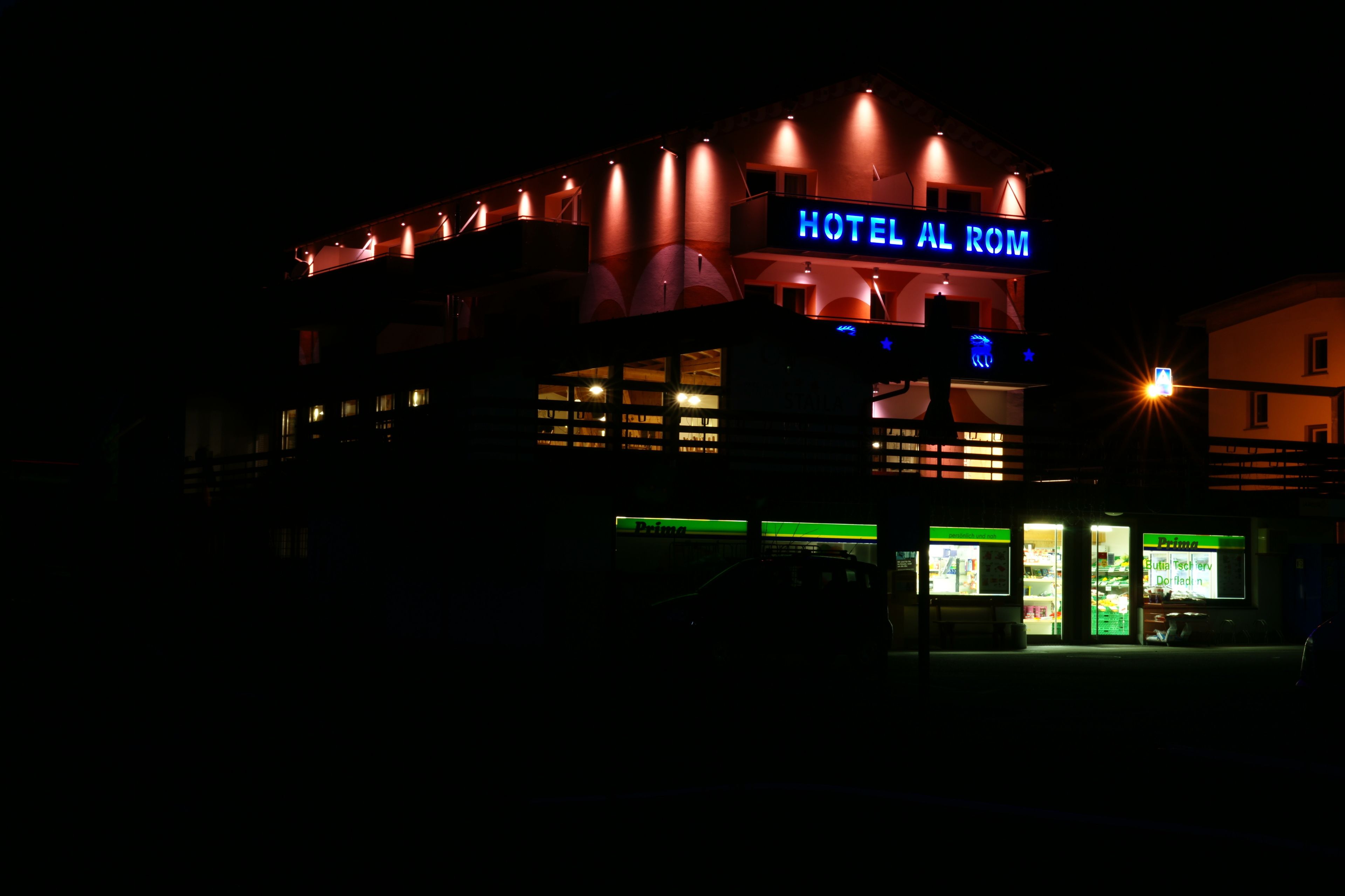 A building with a sign reading "HOTEL AL ROM" at night.