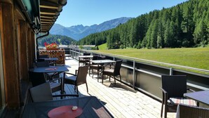 A deck with outdoor seating, overlooking a mountainous landscape. - Hotel Al Rom (Val Muestair)