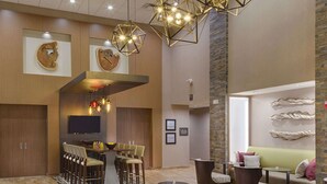 A spacious lobby with a bar area, seating arrangements, and a large rug. - Hampton Inn & Suites Murrieta Temecula (Murrieta)