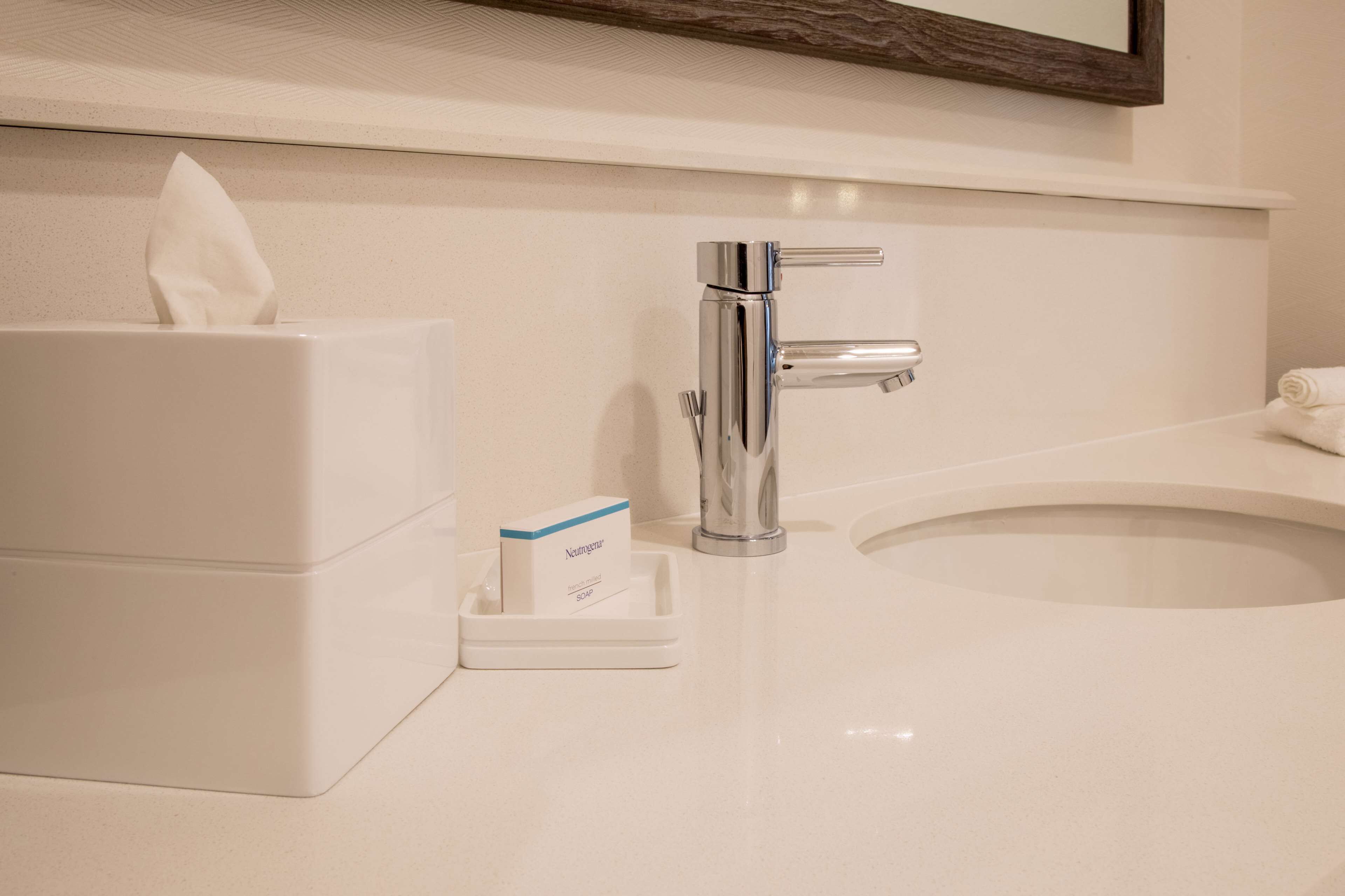 A bathroom with a white sink, a chrome faucet, a tissue box, and a soap dispenser.