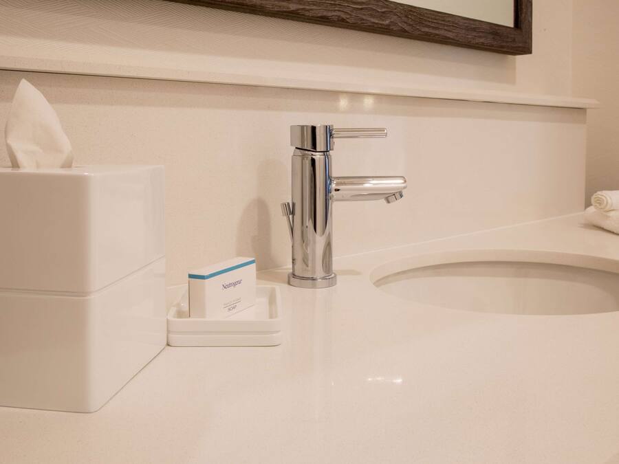 A bathroom with a white sink, a chrome faucet, a tissue box, and a soap dispenser.
