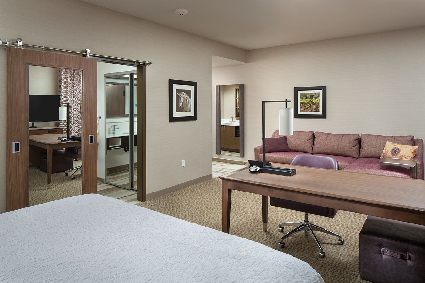A hotel room with a bed, a desk, a sofa, and a kitchenette.