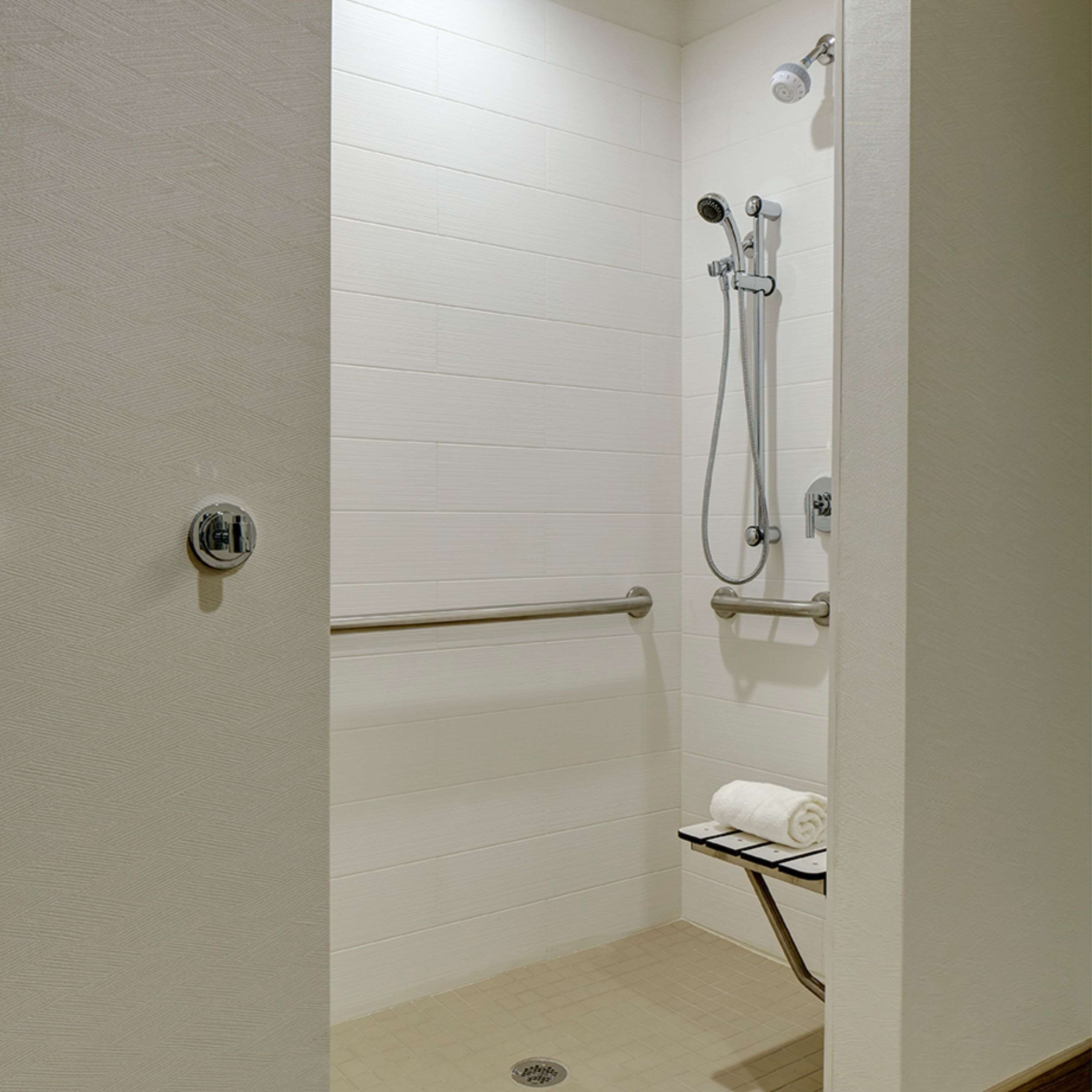 A small, enclosed shower area with a grab bar, a towel rack, and a showerhead.