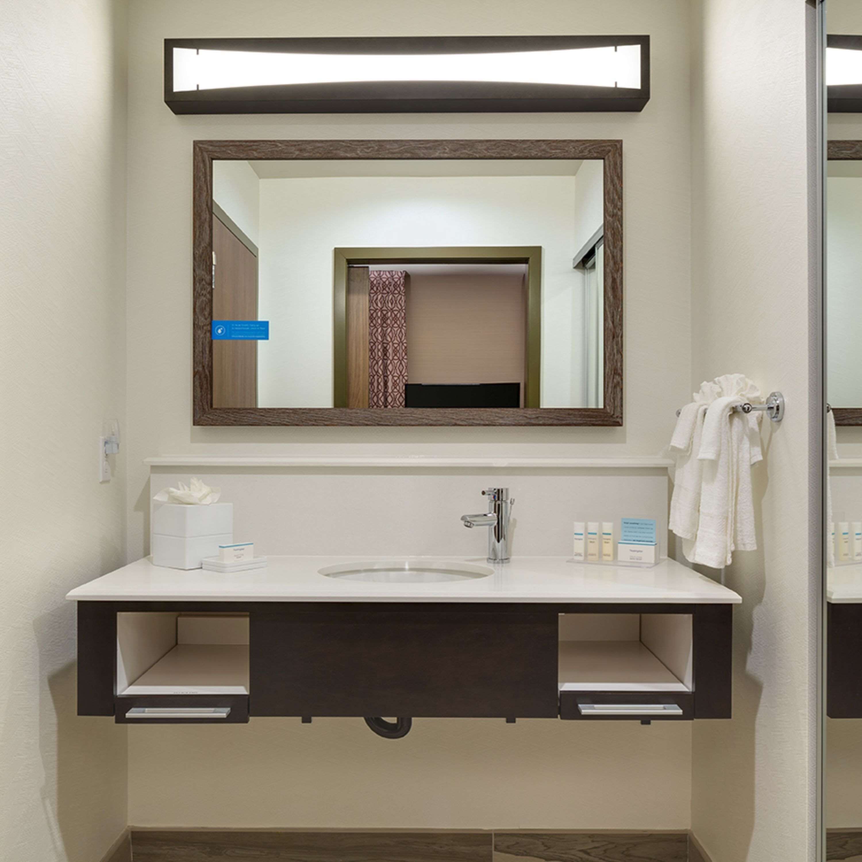 A modern bathroom with a large mirror, a sink, and a towel rack.