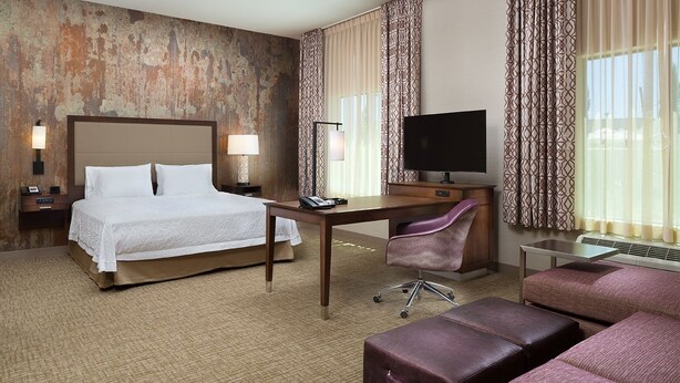 A hotel room with a bed, desk, TV, and seating area. - Hampton Inn & Suites Murrieta Temecula (Murrieta)