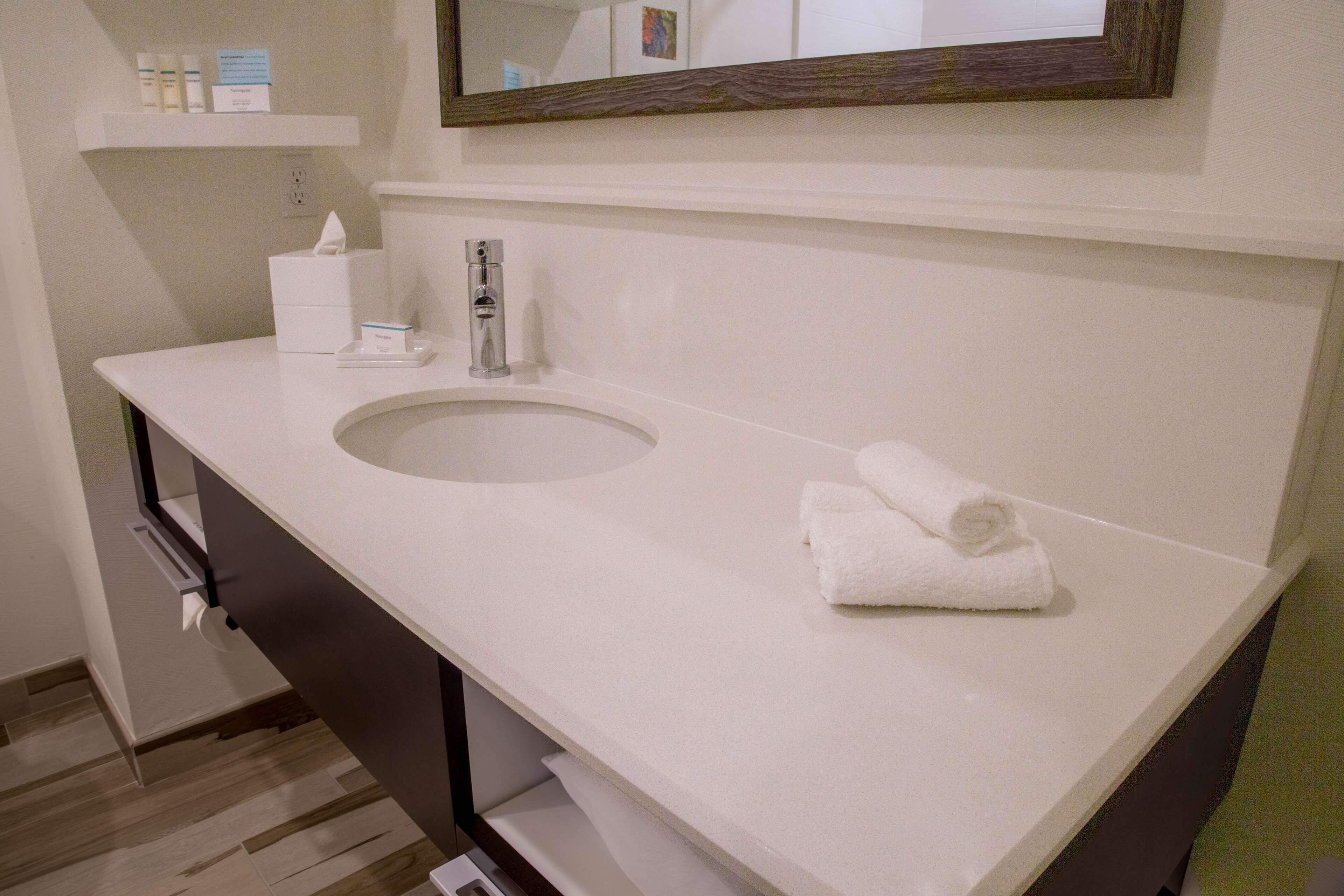 A bathroom with a white sink, a mirror above it, and a towel on the counter.