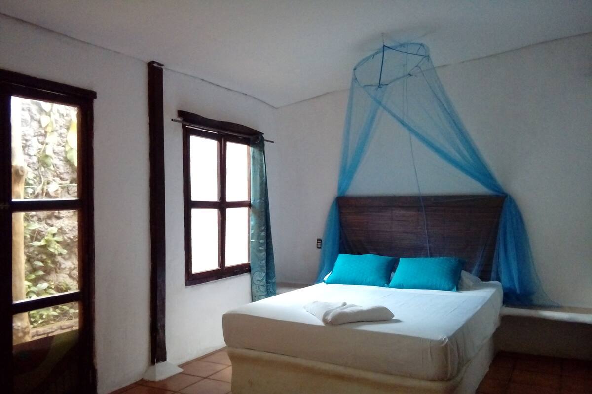 A bedroom with a bed, a window, and a curtain.