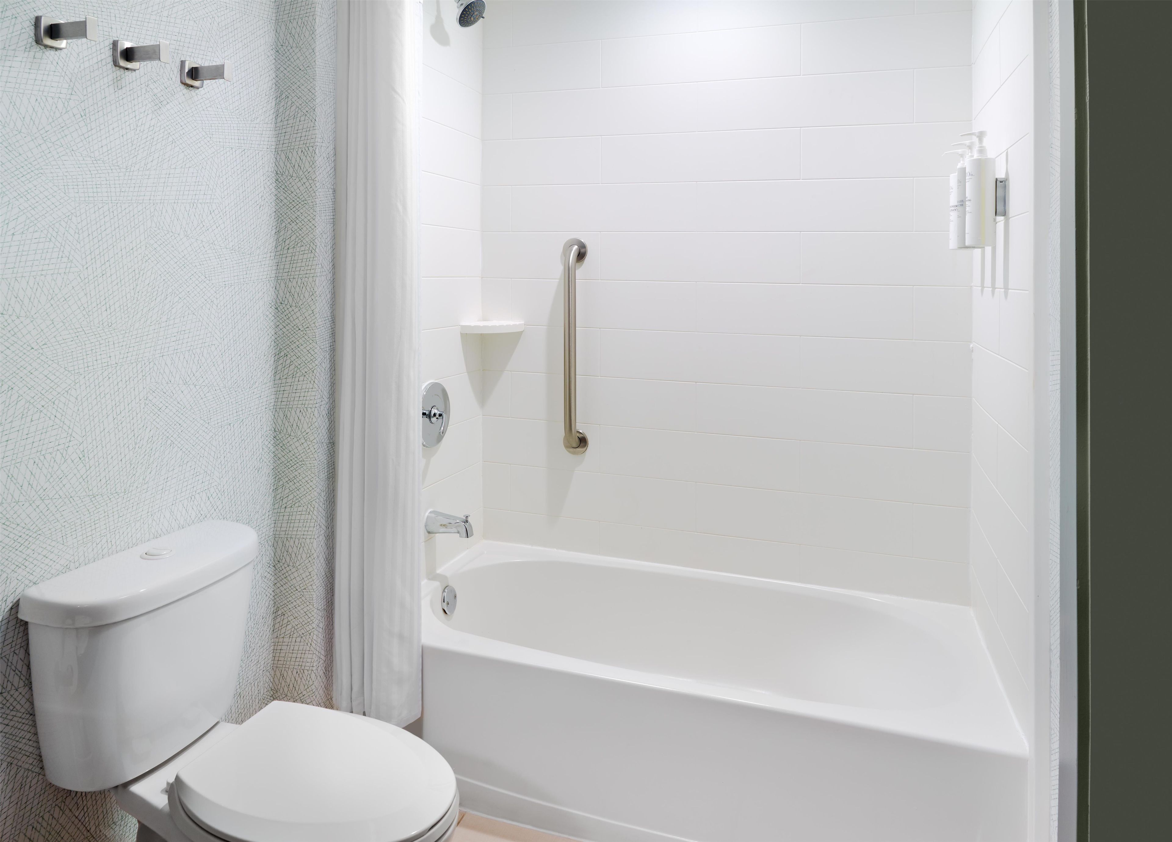 A bathroom with a white toilet, a bathtub, and a shower area.