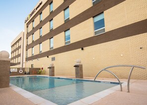 A hotel with a swimming pool, a sign indicating no lifeguard on duty, and a brick facade. - Home2 Suites Newnan (Newnan)
