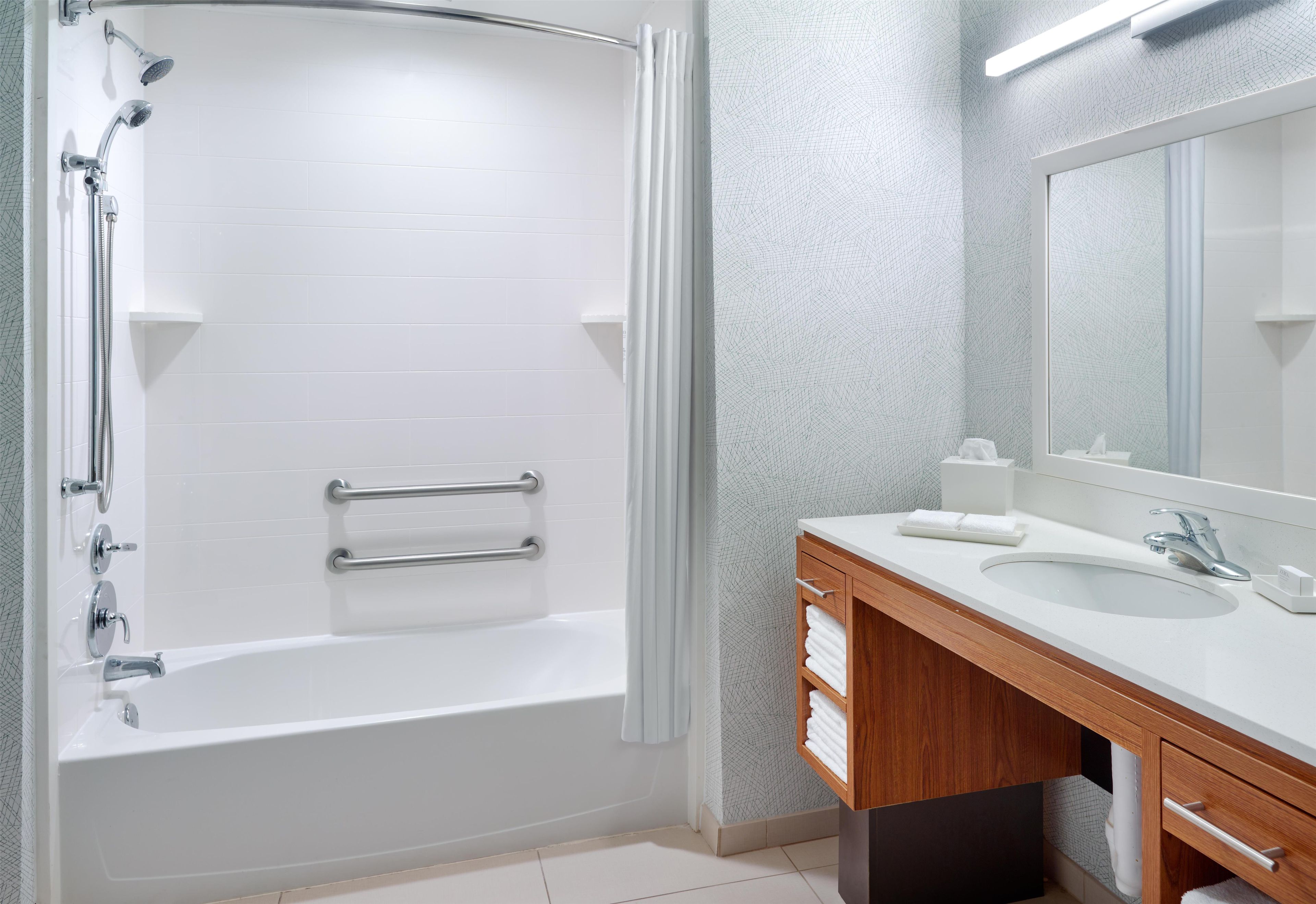 A modern bathroom with a bathtub, a shower, a vanity with a sink, and a mirror.
