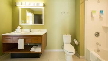 A bathroom with a wooden vanity, a toilet, a bathtub, and a mirror.
