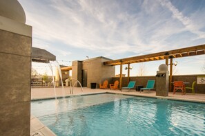 Een seizoensgebonden buitenzwembad en ligstoelen