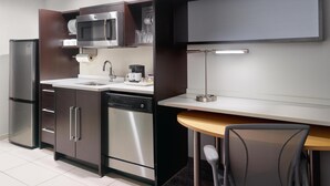 Eine moderne Küche mit Geschirrspüler, Mikrowelle und Kühlschrank, sowie ein Essbereich mit Tisch und Stühlen.