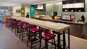 Eine moderne Bar mit einer langen Theke, mehreren Barhocker und einer Kaffeestation.