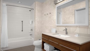 A modern bathroom with a bathtub, toilet, and vanity with a mirror.