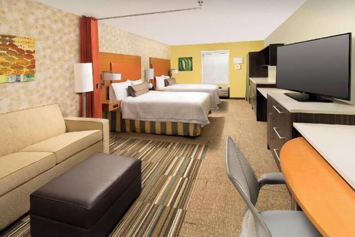 Een hotelkamer met twee bedden, een bank, een televisie en een bureau.