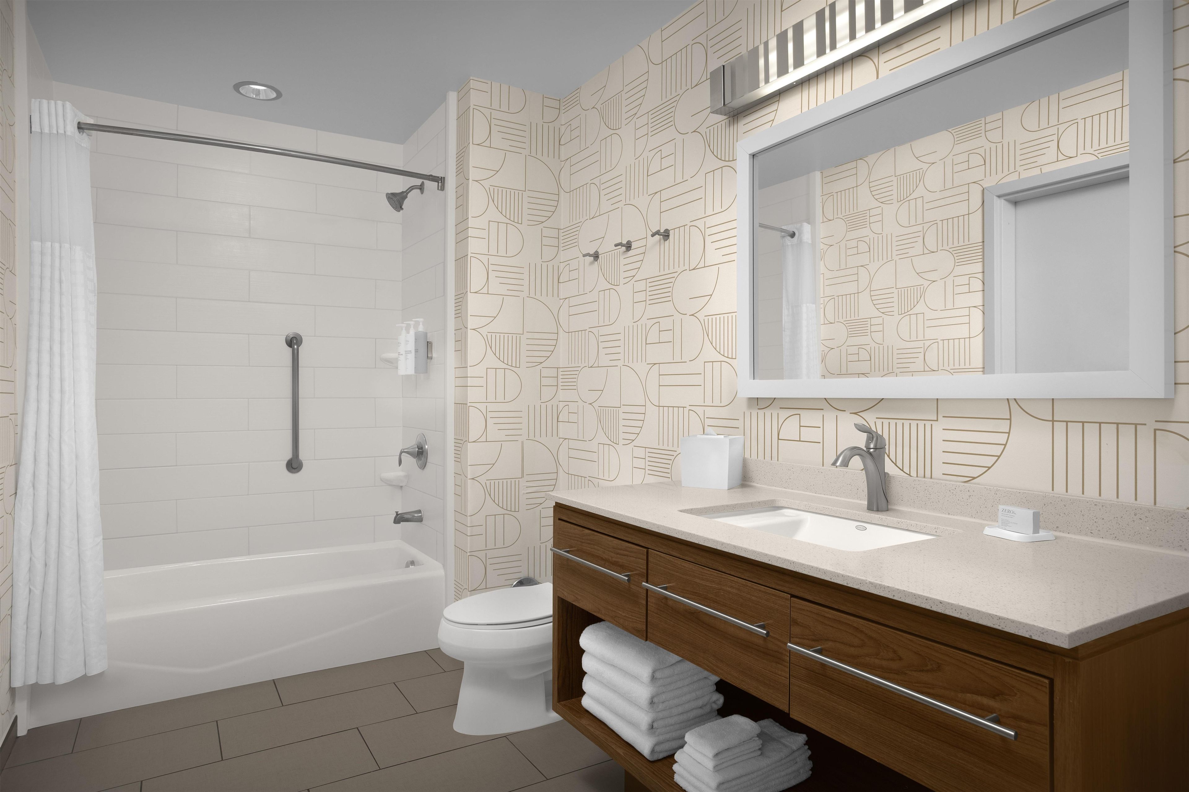Un baño moderno con bañera, inodoro y tocador con espejo.