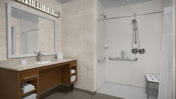 A modern bathroom with a wooden vanity, a large mirror, a shower with a glass door, and a white tiled wall.