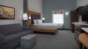 A hotel room with a bed, a sofa, a desk, and a television.