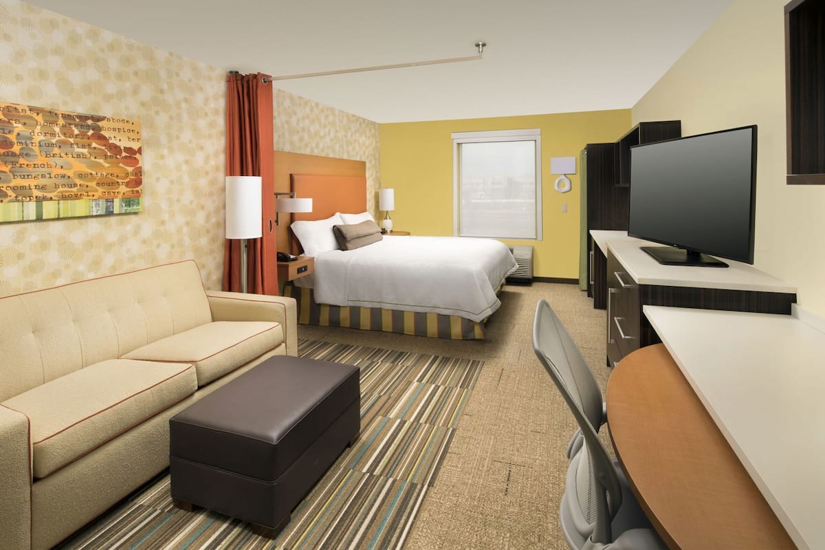 Hotelkamer met een bed, een bank, een televisie, een bureau en een kamerbreed tapijt met dessin.