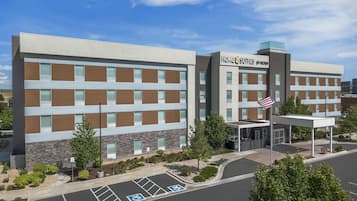 A modern hotel with a flat roof, multiple windows, and a parking lot with handicapped accessible spaces.