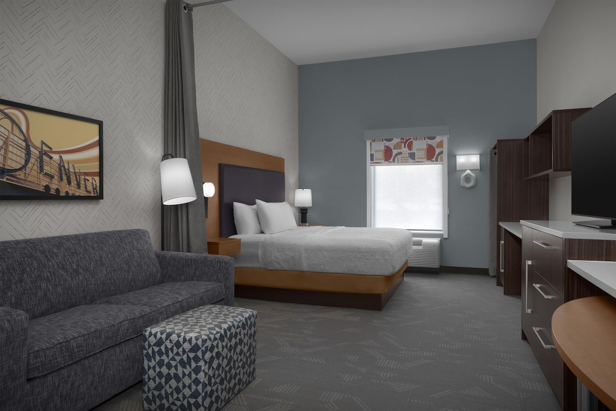 Een hotelkamer met een bed, een bank, een bureau en een televisie.