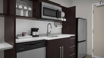 A modern kitchen with a built-in microwave, coffee maker, dishwasher, and a refrigerator.