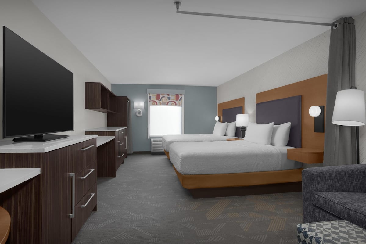 Een hotelkamer met een televisie, twee bedden, een bureau en een bank.