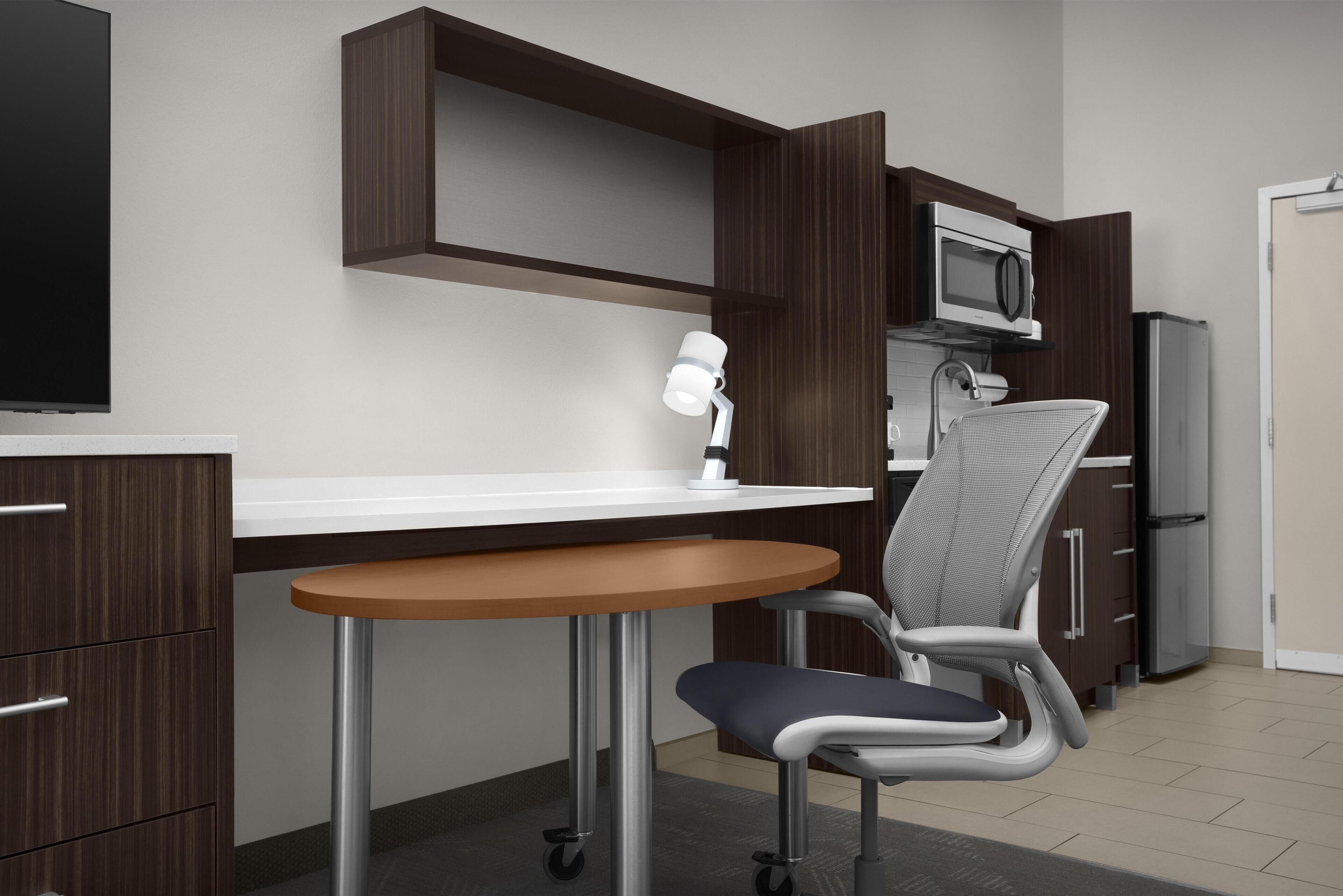 A modern kitchen with a microwave, refrigerator, and a dining area with a table and chair.