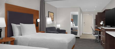 Habitación de hotel con dos camas, un escritorio, televisión y baño.