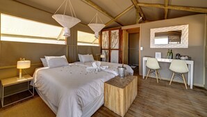 A hotel room with a large bed, a wooden nightstand, a desk with two chairs, and a wooden coffee table. - Kanaan N/a'an ku sê Desert Retreat (Kanaan)