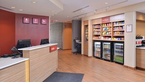 A reception area with a wooden reception desk, a "Hello" sign, a "Stay" sign, a "Work" sign, a "Play" sign, and a snack vending machine labeled "In a Pinch". - TownePlace Suites by Marriott Gillette (Gillette)