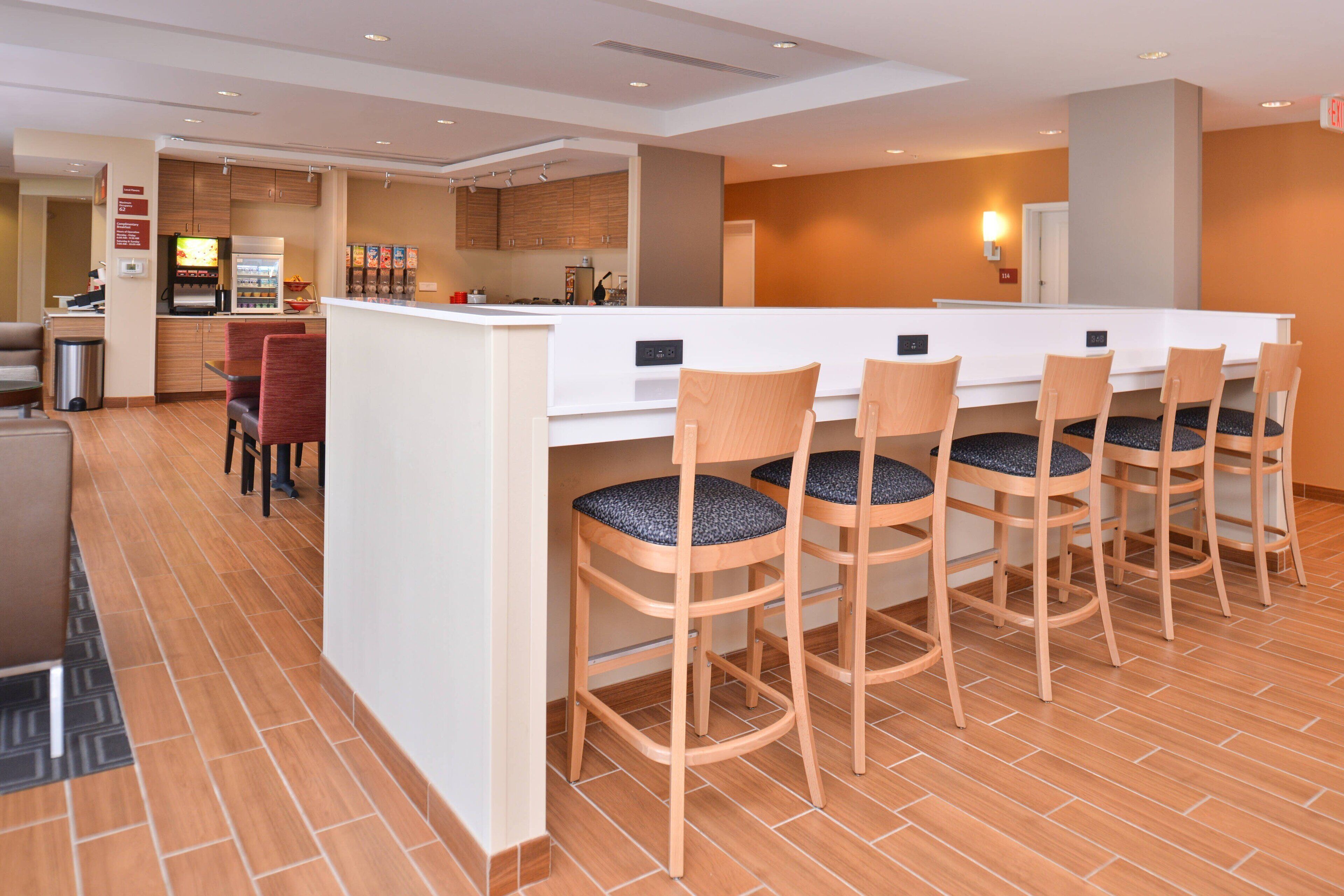 A modern kitchen with a central island, bar stools, and a seating area with a sofa and chairs.