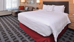 A hotel room with a large bed, a sofa, a desk, and a window with curtains. - TownePlace Suites by Marriott Gillette (Gillette)