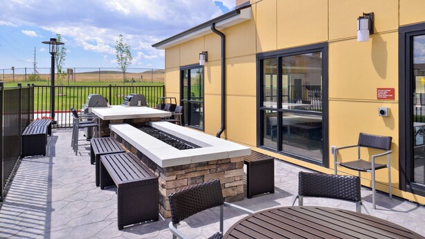 An outdoor patio area with a stone fireplace, seating, and grilling equipment. - TownePlace Suites by Marriott Gillette (Gillette)