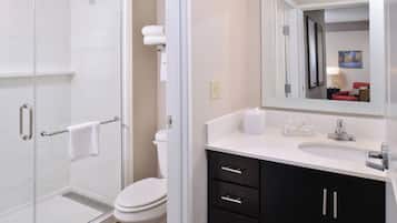 A modern bathroom with a glass shower enclosure, a white toilet, and a vanity with black cabinets and a white countertop.
