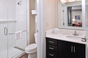 A modern bathroom with a glass shower enclosure, a white toilet, and a vanity with black cabinets and a white countertop. - TownePlace Suites by Marriott Gillette (Gillette)