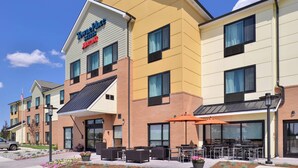 A hotel with a modern design, featuring a prominent sign, outdoor seating area, and a clear sky. - TownePlace Suites by Marriott Gillette (Gillette)