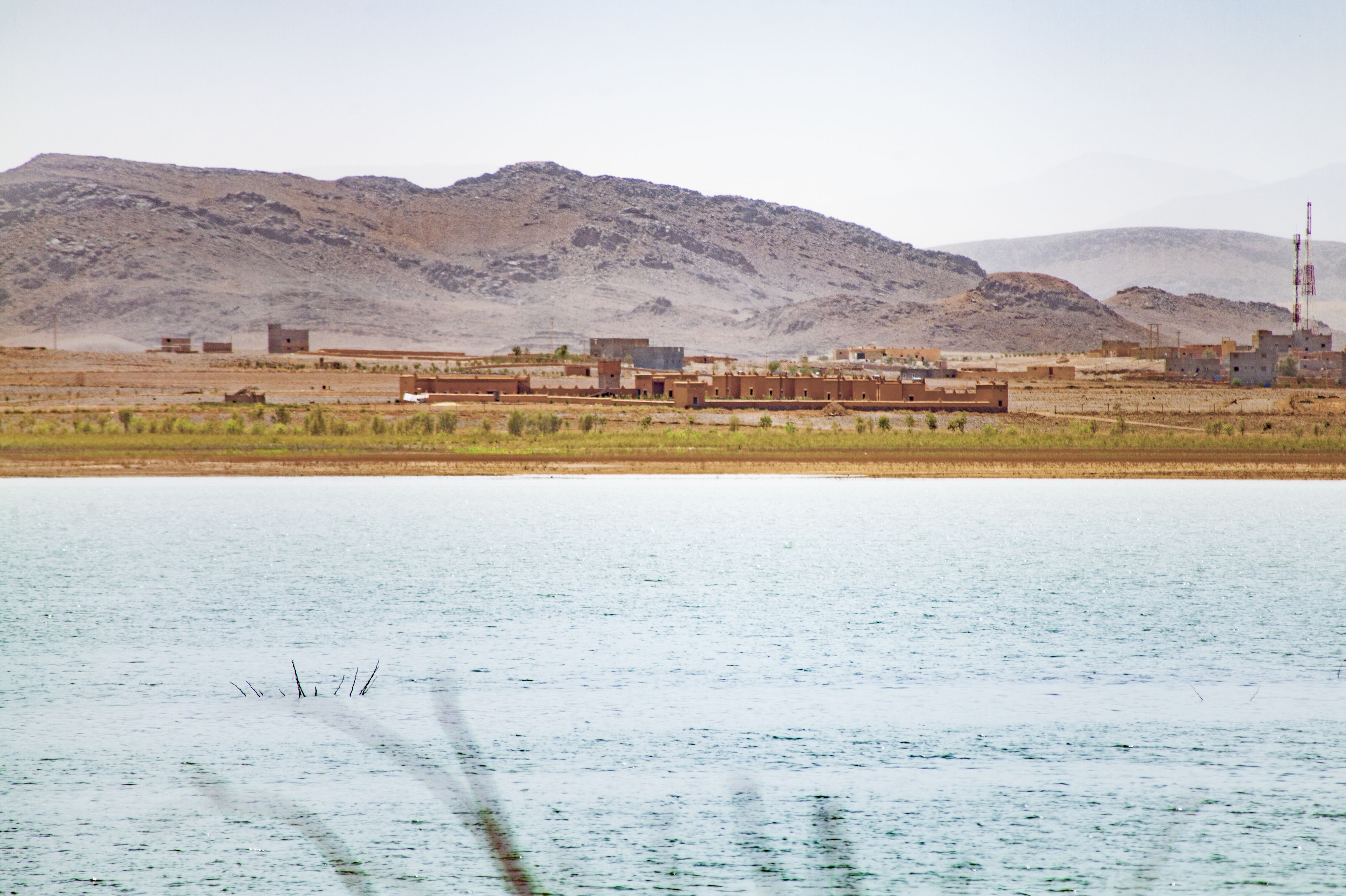 A desert landscape with buildings and a body of water.