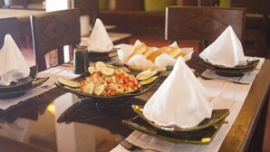 A dining table with plates of food, napkins, and a bottle of water. - Ecolodge l Ile de Ouarzazate (Tarmigt)