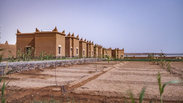 A row of traditional adobe buildings with a stone wall in the foreground. - Ecolodge l Ile de Ouarzazate (Tarmigt)