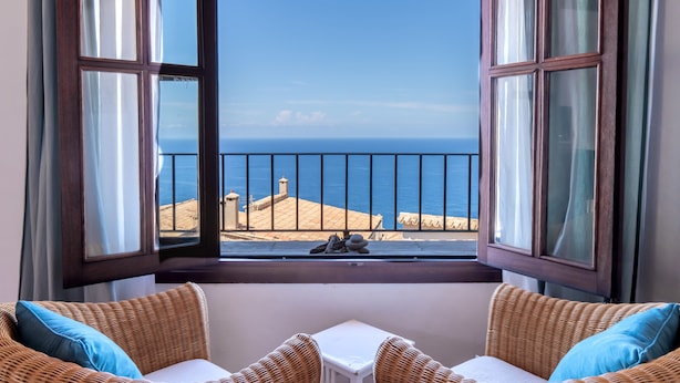 A room with a view of the sea through a large window with curtains. - Hotel Son Borguny (Banyalbufar)