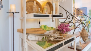 A multi-tiered wooden shelf with woven baskets, a brass trombone, and a vase of flowers. - Hotel Son Borguny (Banyalbufar)