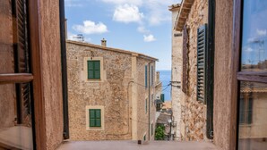 A narrow street with stone buildings, green shutters, and a clear view of the sea. - Hotel Son Borguny (Banyalbufar)