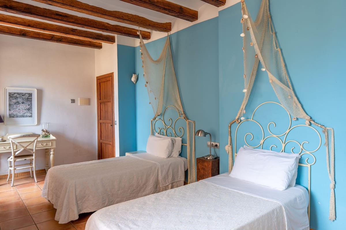 Un dormitorio con dos camas, vigas de techo de madera y una pared azul.