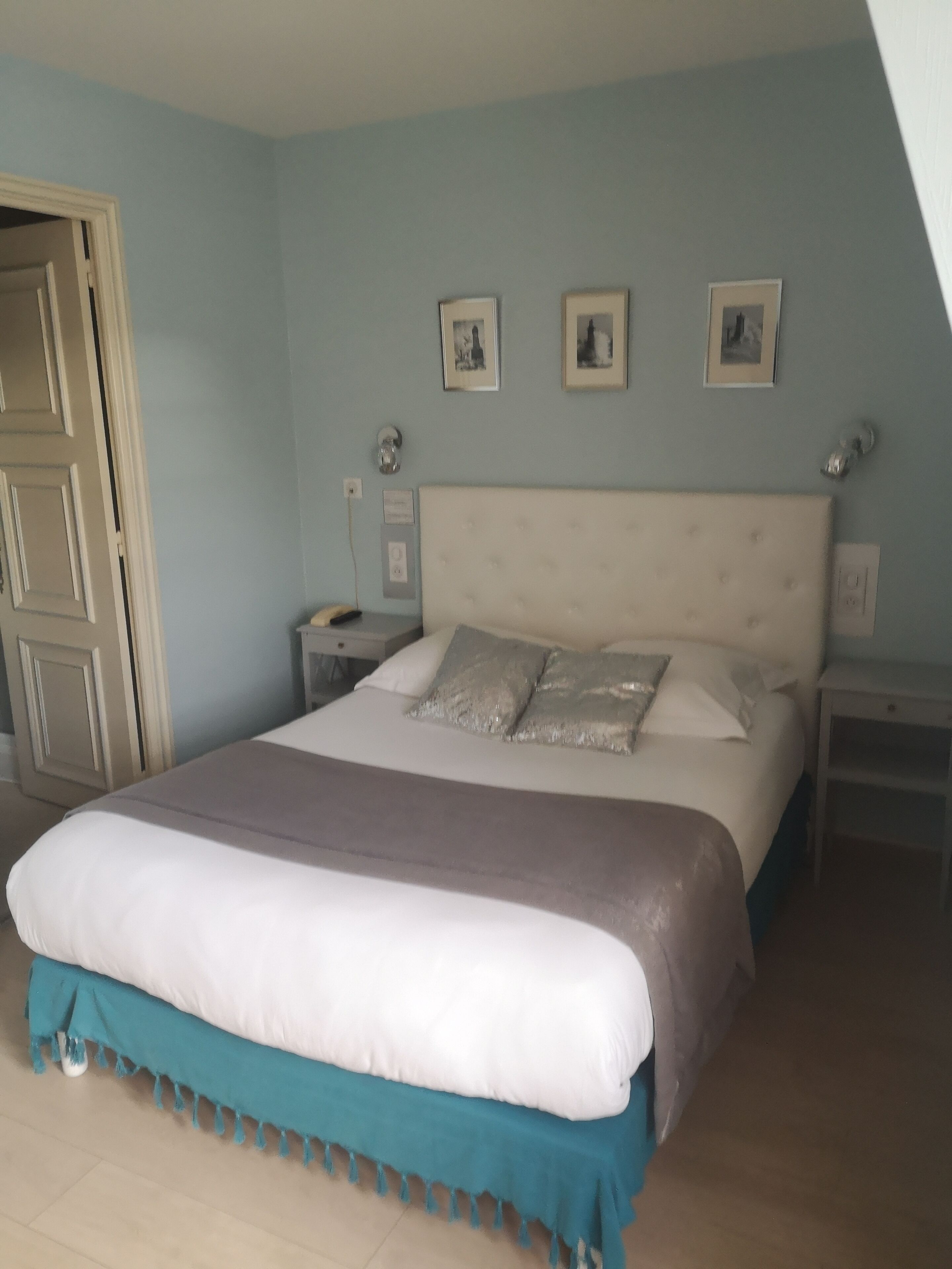 A bedroom with a large bed, a nightstand, a dresser, and a door.